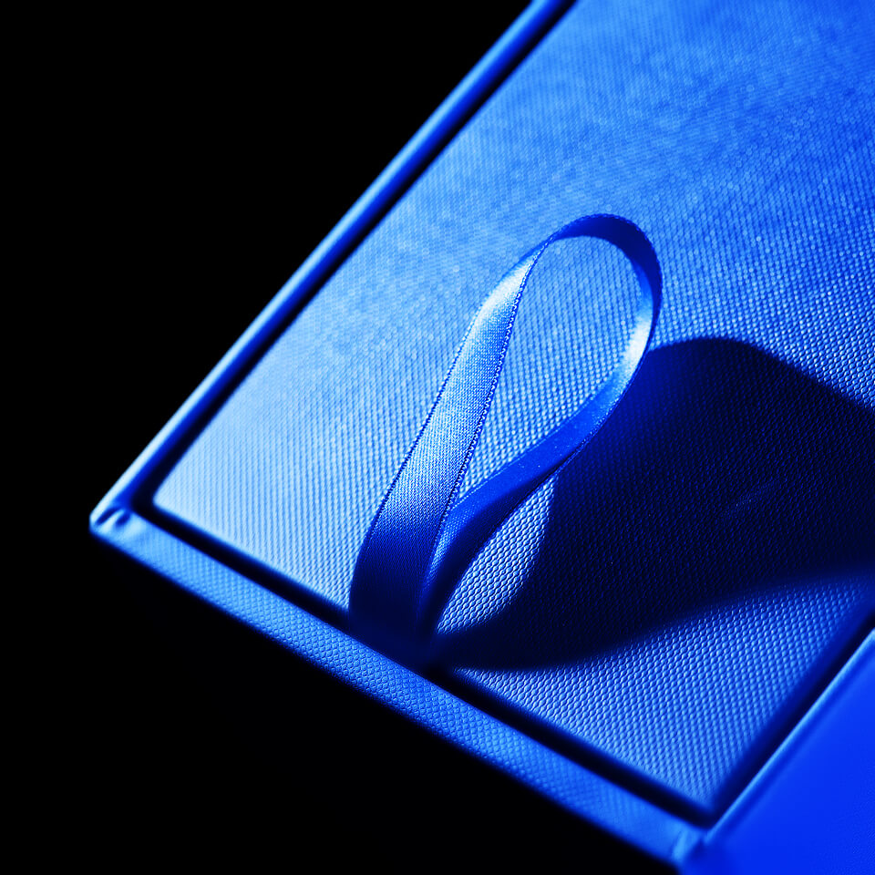 Blauer Schuber mit umlaufendem Band, geöffnet auf heller Fläche